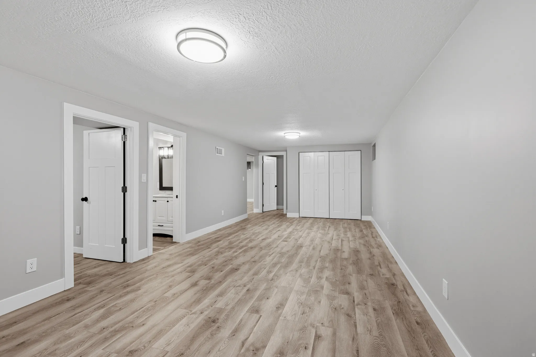 Lower level gathering space with fireplace, laminate flooring, fresh neutral paint and LED lighting