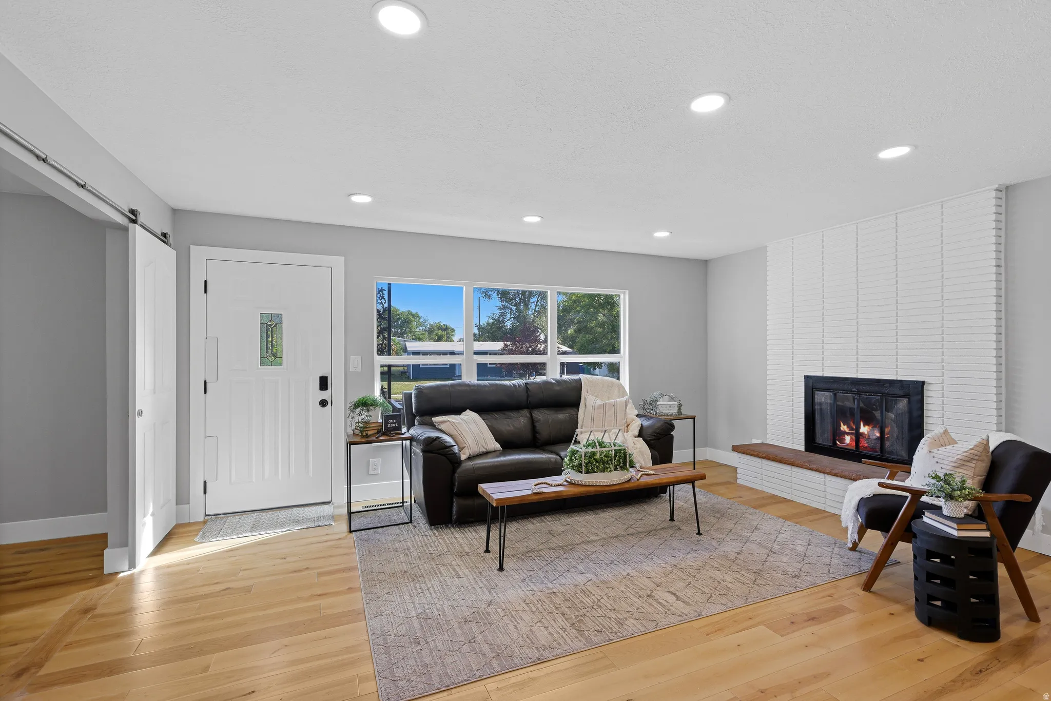 Open floor plan, recessed lighting, hardwood flooring and a classic fireplace