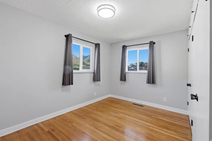 Main floor bedroom with double updated windows, hardwood flooring and fresh neutral paint