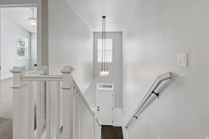 Two-story entry with white balusters and handrail, dark wood-finish flooring, and a pendant light fixture