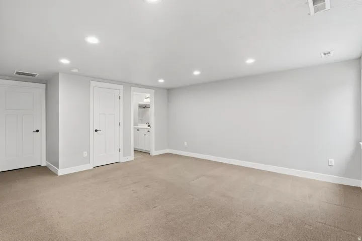Recessed ceiling lighting, light gray wall finishes, white trim, paneled interior doors, and neutral carpet