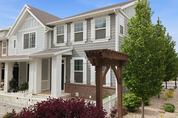 Siding exterior with brick accents, covered entryways, white picket fence, and a wooden pergola structure