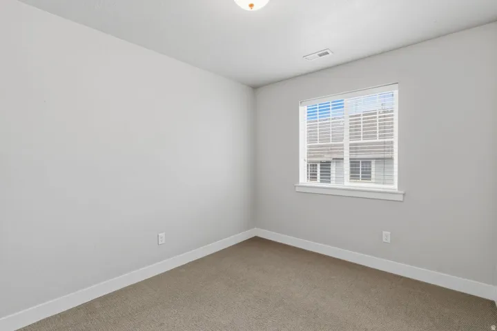 Carpeted flooring, neutral wall tones, white trim, and a window with blinds