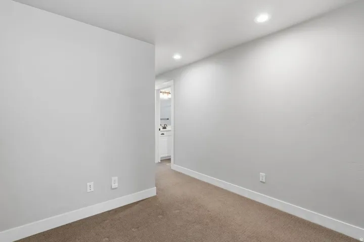 Recessed ceiling lighting illuminates the wall-to-wall carpeting and neutral wall tones