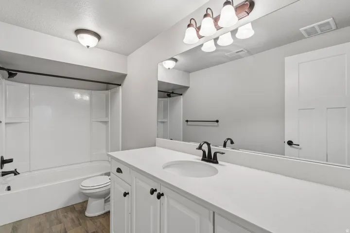 White shaker-style vanity with dark hardware, integrated sink, and light-toned countertop