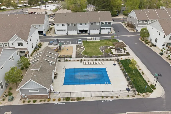 Community pool with a covered pool house, adjacent patio with lounge seating, and a nearby playground