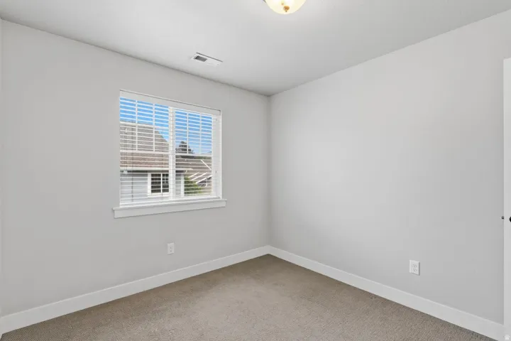 Neutral wall color, carpeted flooring, window with blinds, and flush mount lighting