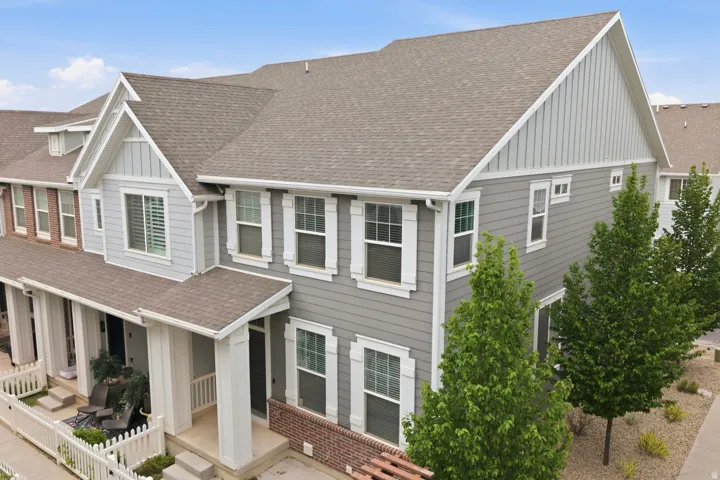 Multi-level townhome exterior featuring gray siding, white window trim, and a prominent gable roofline