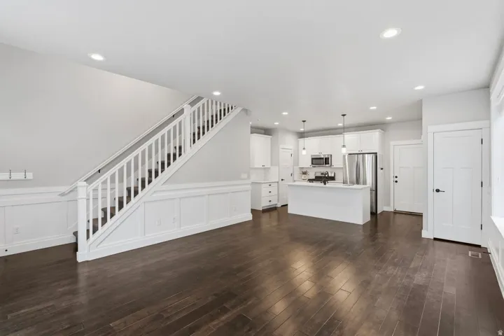 Wood-finish flooring throughout, white paneled wainscoting, and recessed lighting