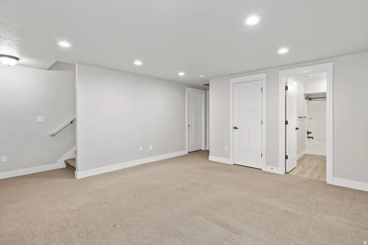 Recessed ceiling lighting, carpeted flooring, white trim, and a full bathroom with a tiled floor