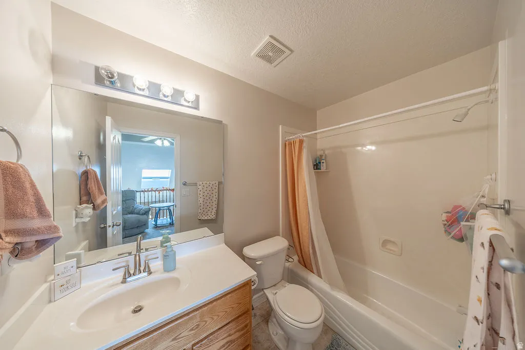 Bathroom featuring a single vanity, wood-finish cabinetry, a large wall-mounted mirror, a four-bulb vanity light fixture, and a combination bathtub and shower with a showerhead
