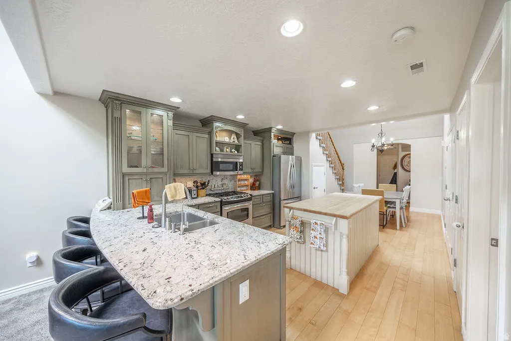 Kitchen featuring light-toned cabinetry, stainless steel appliances, a center island with a wood-finish top, and a breakfast bar with a speckled countertop