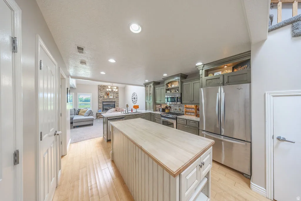 Kitchen with wood-finish flooring, two islands, and green cabinetry