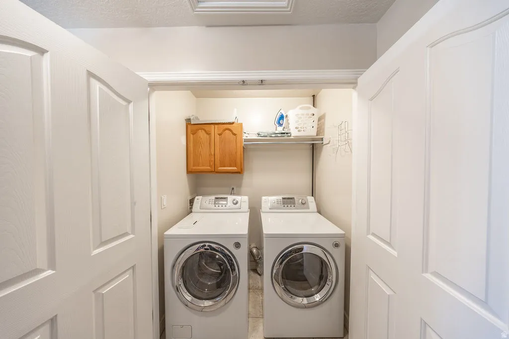 Laundry closet with dual front-load appliances, built-in shelving, and wood-finish cabinetry