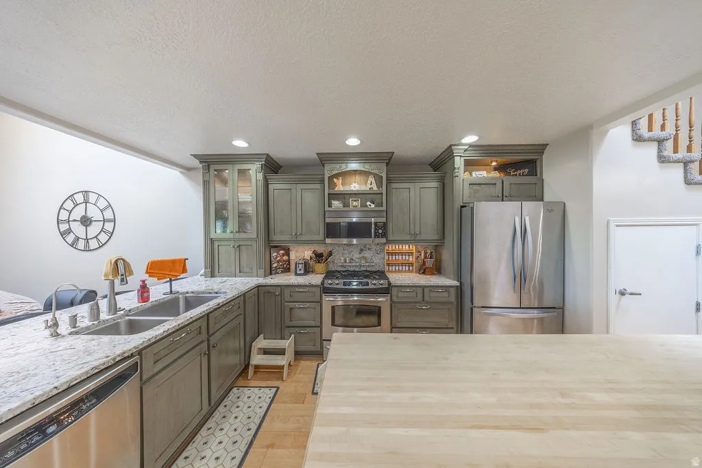 Kitchen featuring granite countertops, stainless steel appliances, custom cabinetry, recessed lighting, and a double basin sink