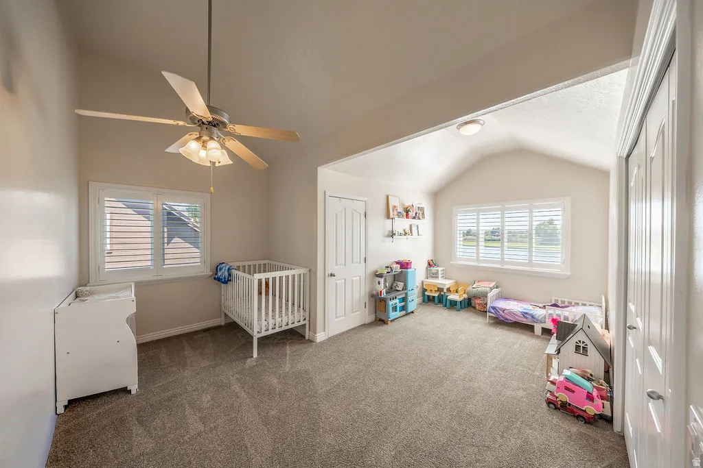Vaulted ceilings, plush carpet, white plantation shutters, and a ceiling fan with integrated lighting