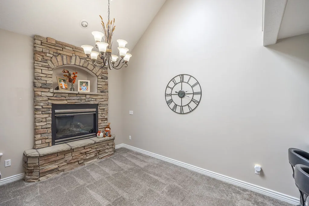 Stone-clad fireplace with an arched niche, vaulted ceiling, and recessed lighting