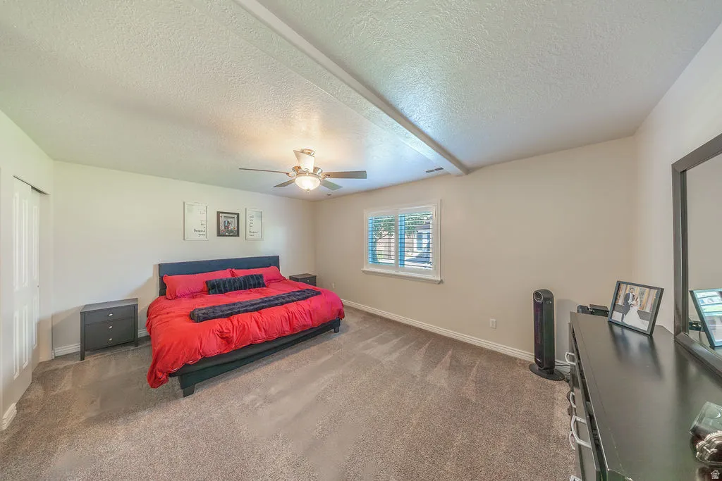 Carpeted flooring, ceiling fan, white window shutters, and a closet with bifold doors