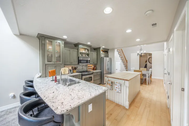 Kitchen featuring light-toned cabinetry, stainless steel appliances, a center island with a wood-finish top, and a breakfast bar with a speckled countertop