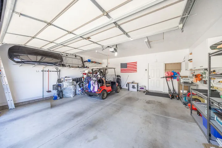 Concrete flooring, white walls, overhead garage door, built-in storage shelving, and a white entry door