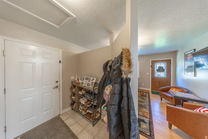 Entryway featuring a paneled door, tile flooring, and vaulted ceiling