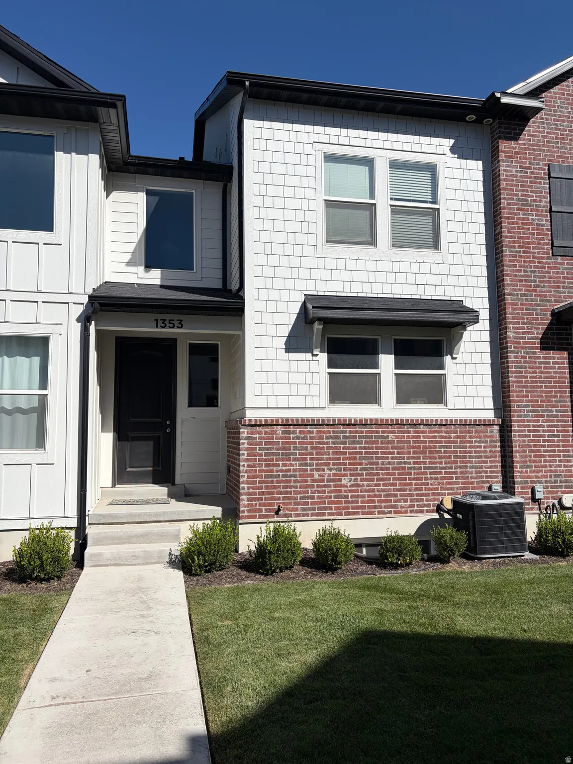 Two-story exterior featuring white shingle and board and batten siding with a brick facade