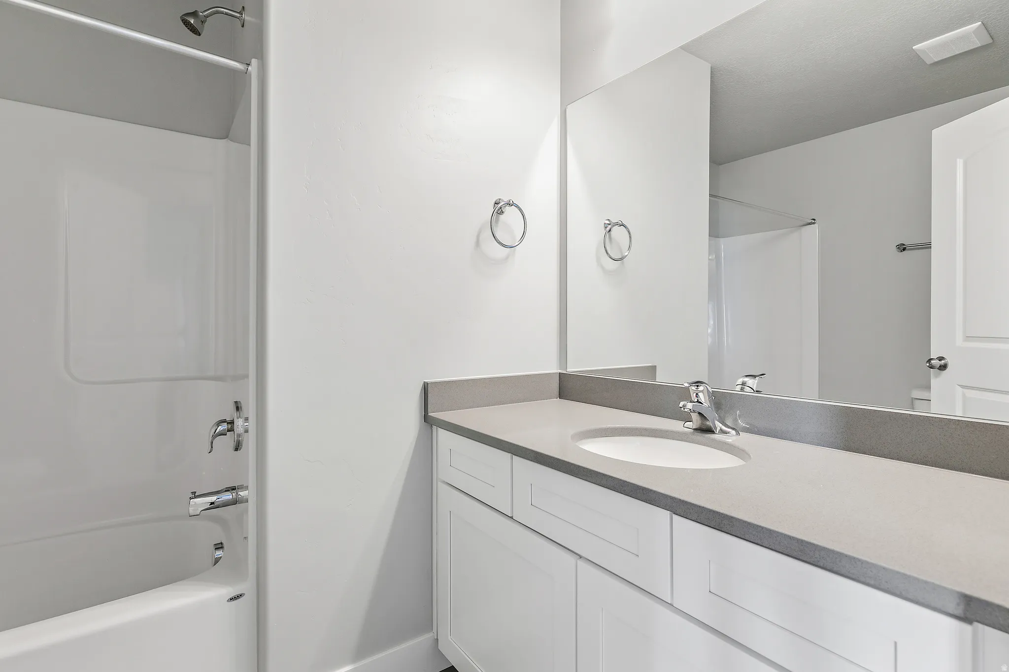 White vanity with an integrated sink, polished chrome faucet, and expansive wall-mounted mirror