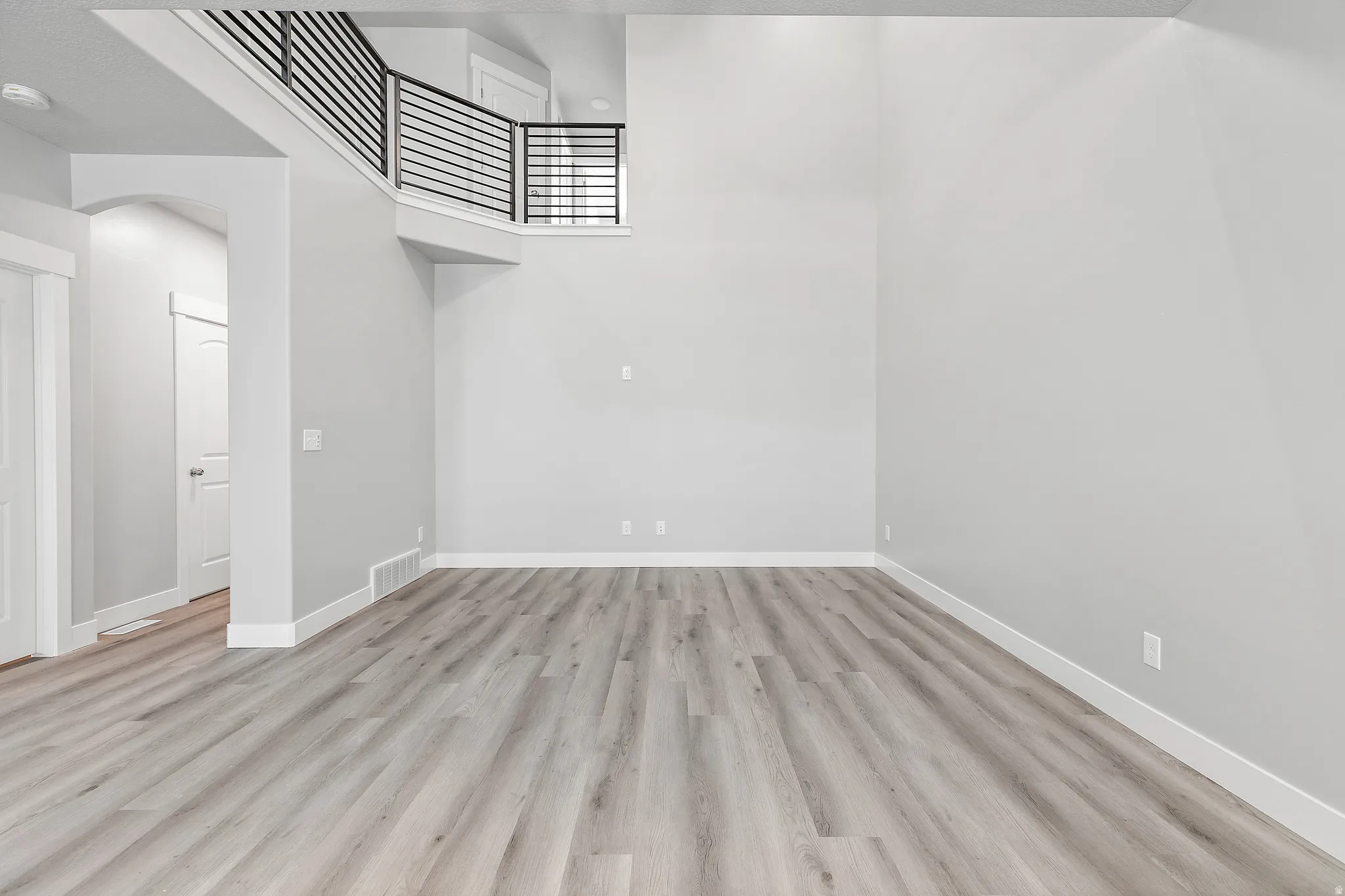 Vaulted ceilings, wood-finish flooring, and a contemporary second-story railing with horizontal balusters