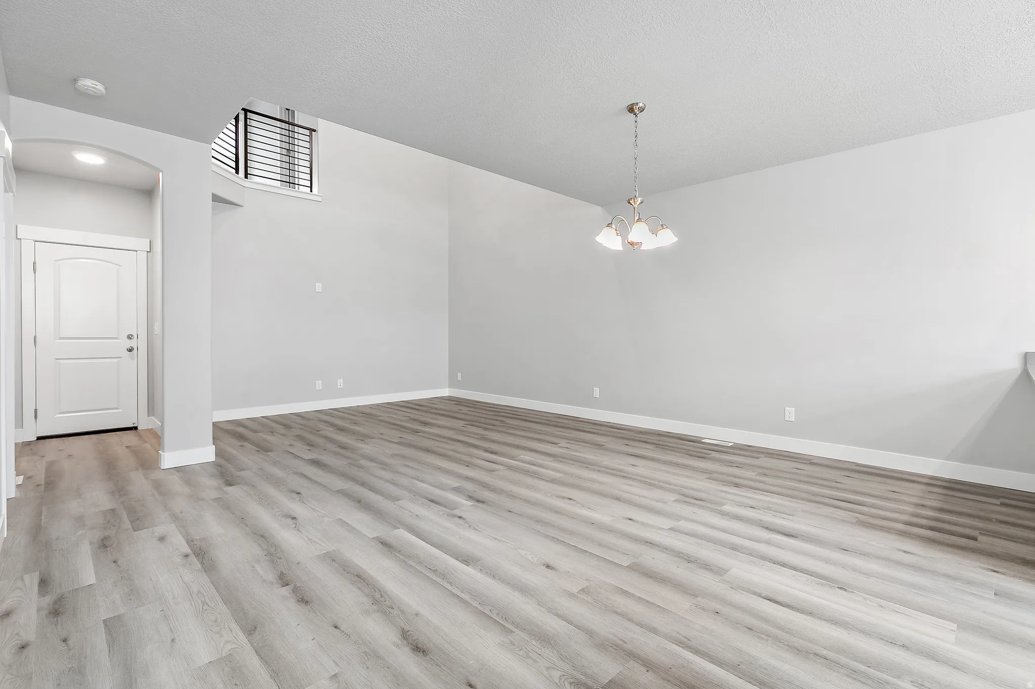 Wood-finish flooring throughout, featuring a vaulted ceiling and a decorative arched entryway