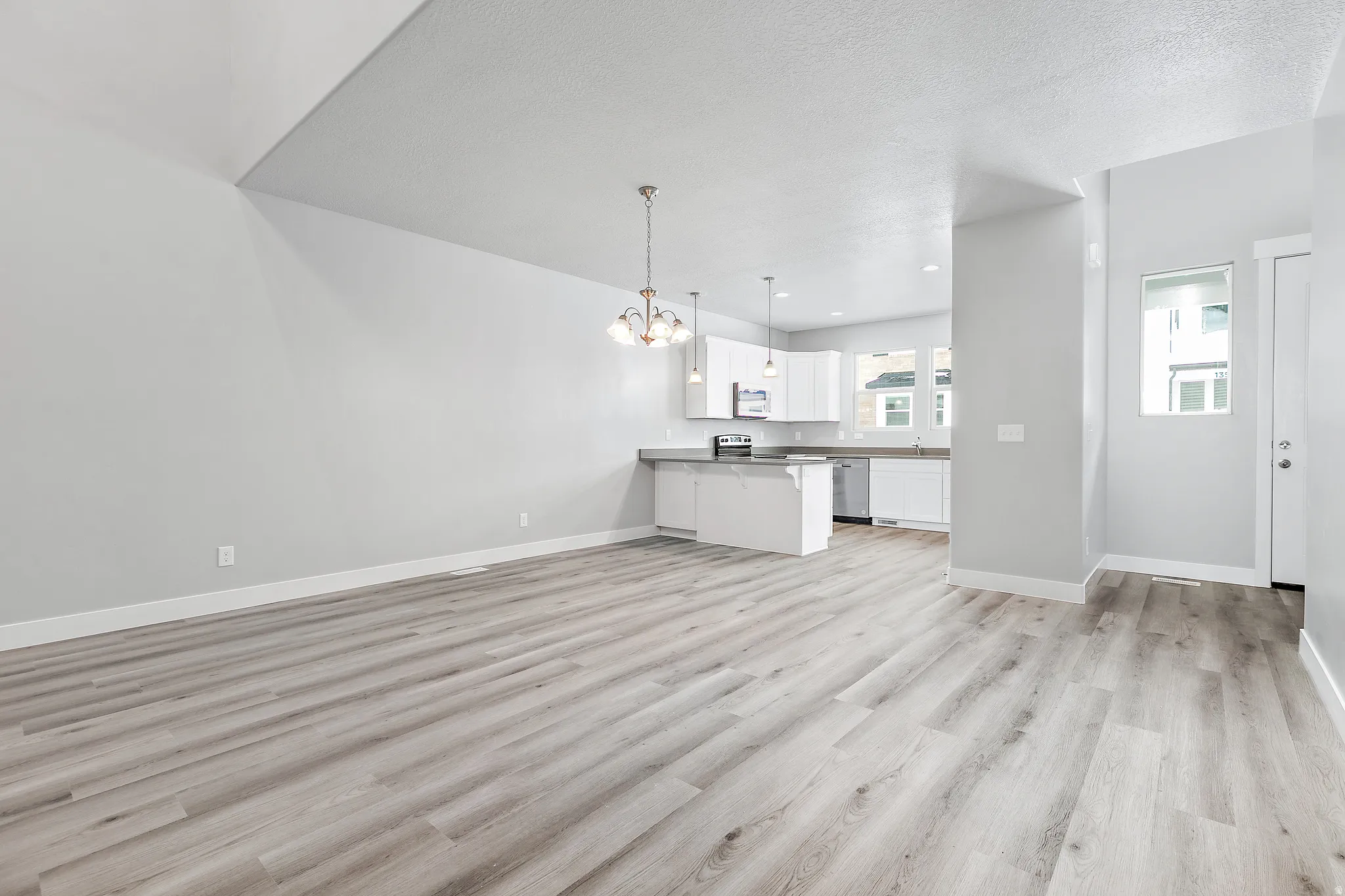 Open-concept living space with wood-finish flooring, recessed lighting, and a vaulted ceiling