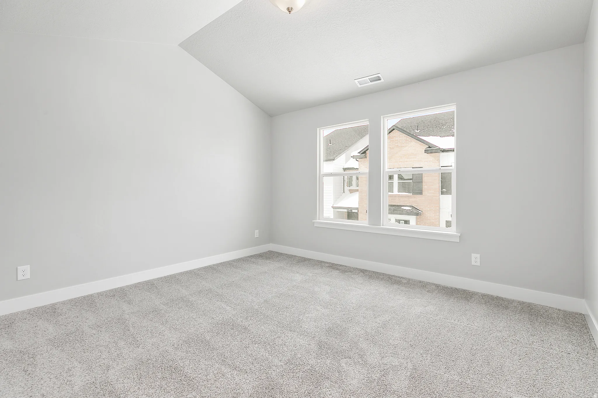 Vaulted ceiling, two windows, wall-to-wall carpeting, neutral wall paint, and overhead lighting