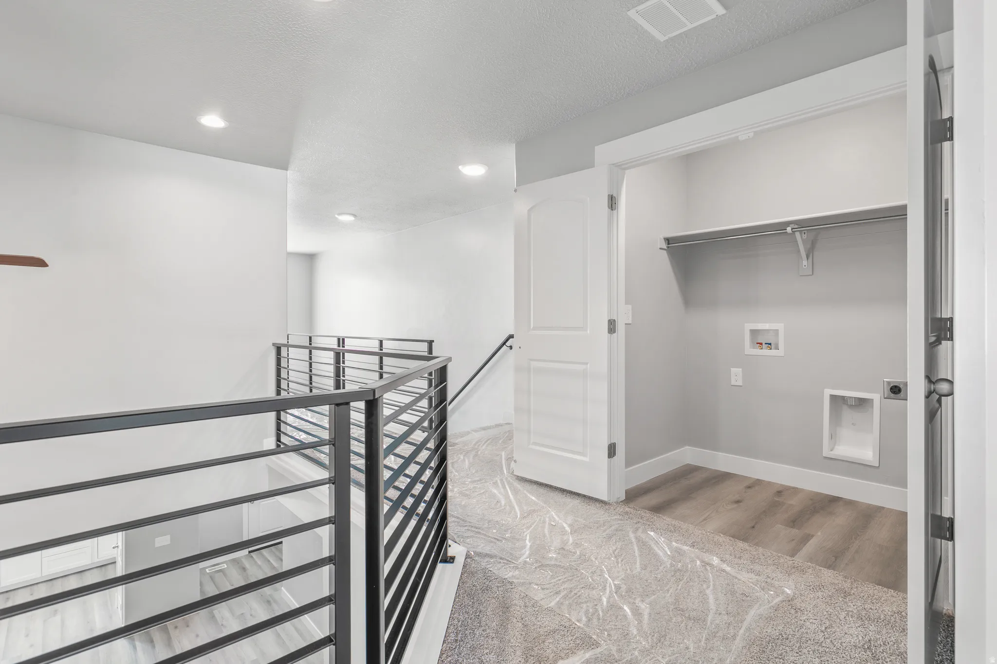 Recessed lighting, contemporary metal railing, built-in shelving, laundry hookups, and wood-finish flooring