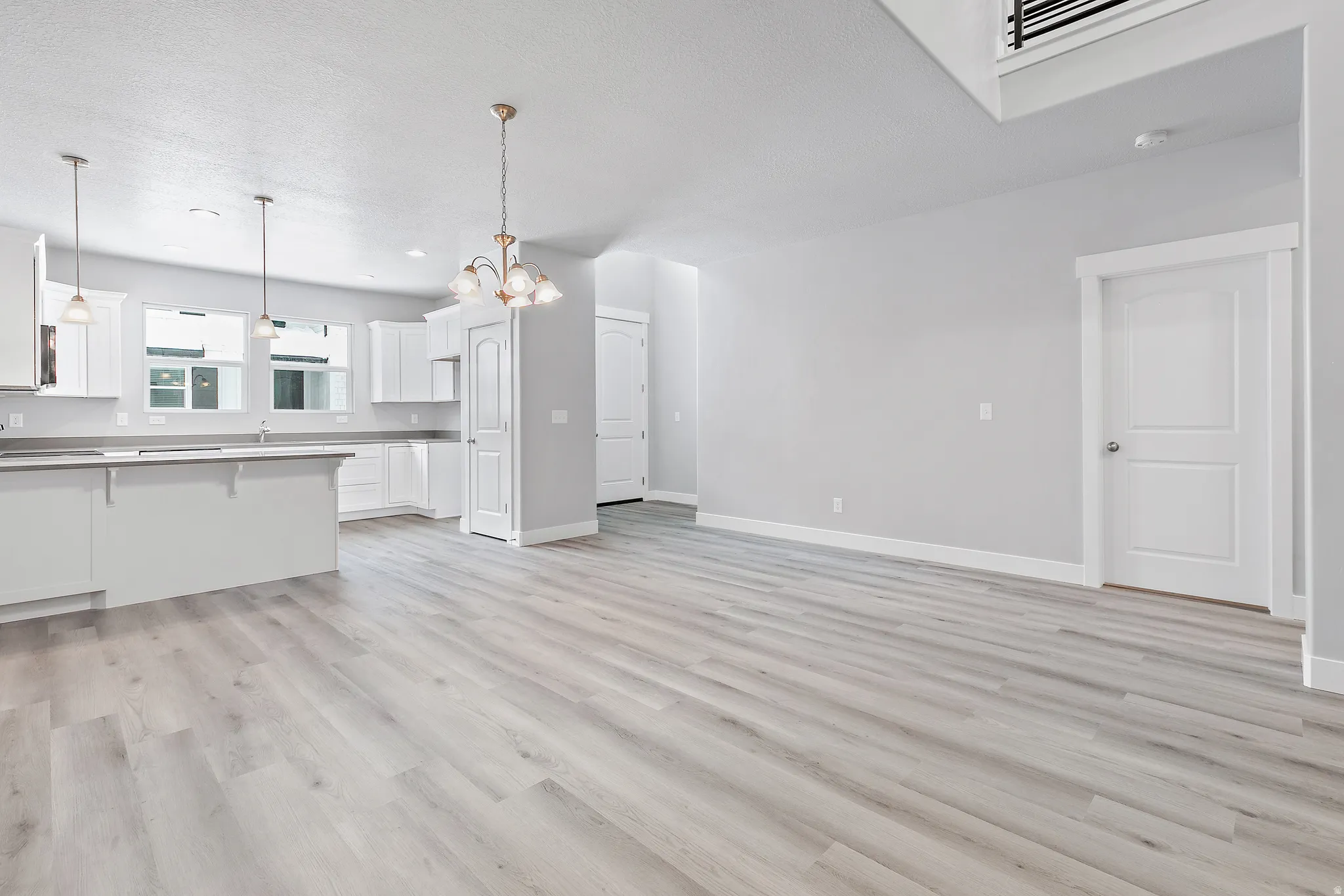 Open-concept living space featuring wood-finish flooring, a kitchen island, white cabinetry, and recessed lighting