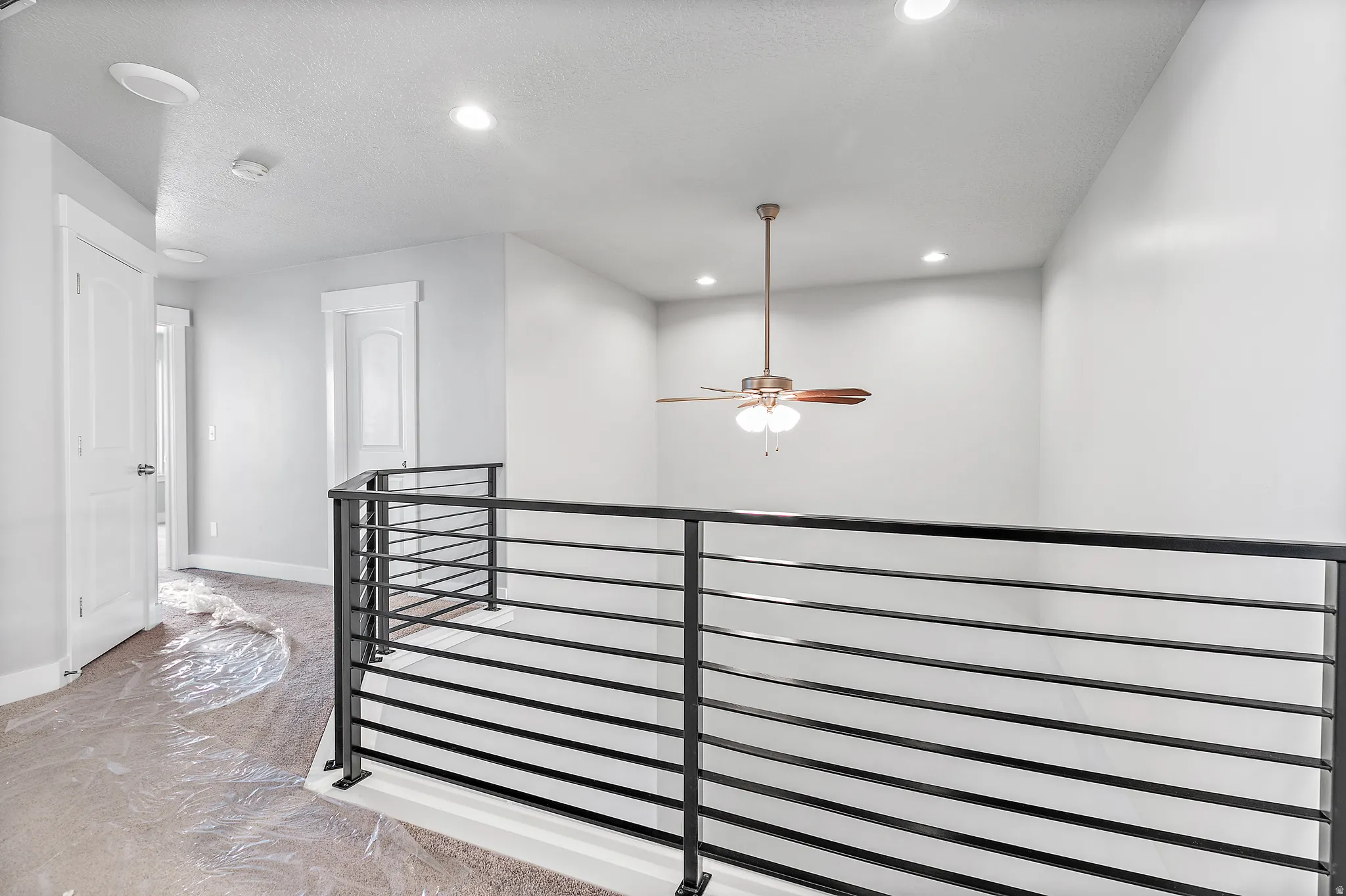 Open loft area featuring contemporary horizontal metal railing and a ceiling fan