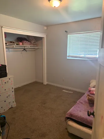 Carpeted interior space with a window featuring horizontal blinds
