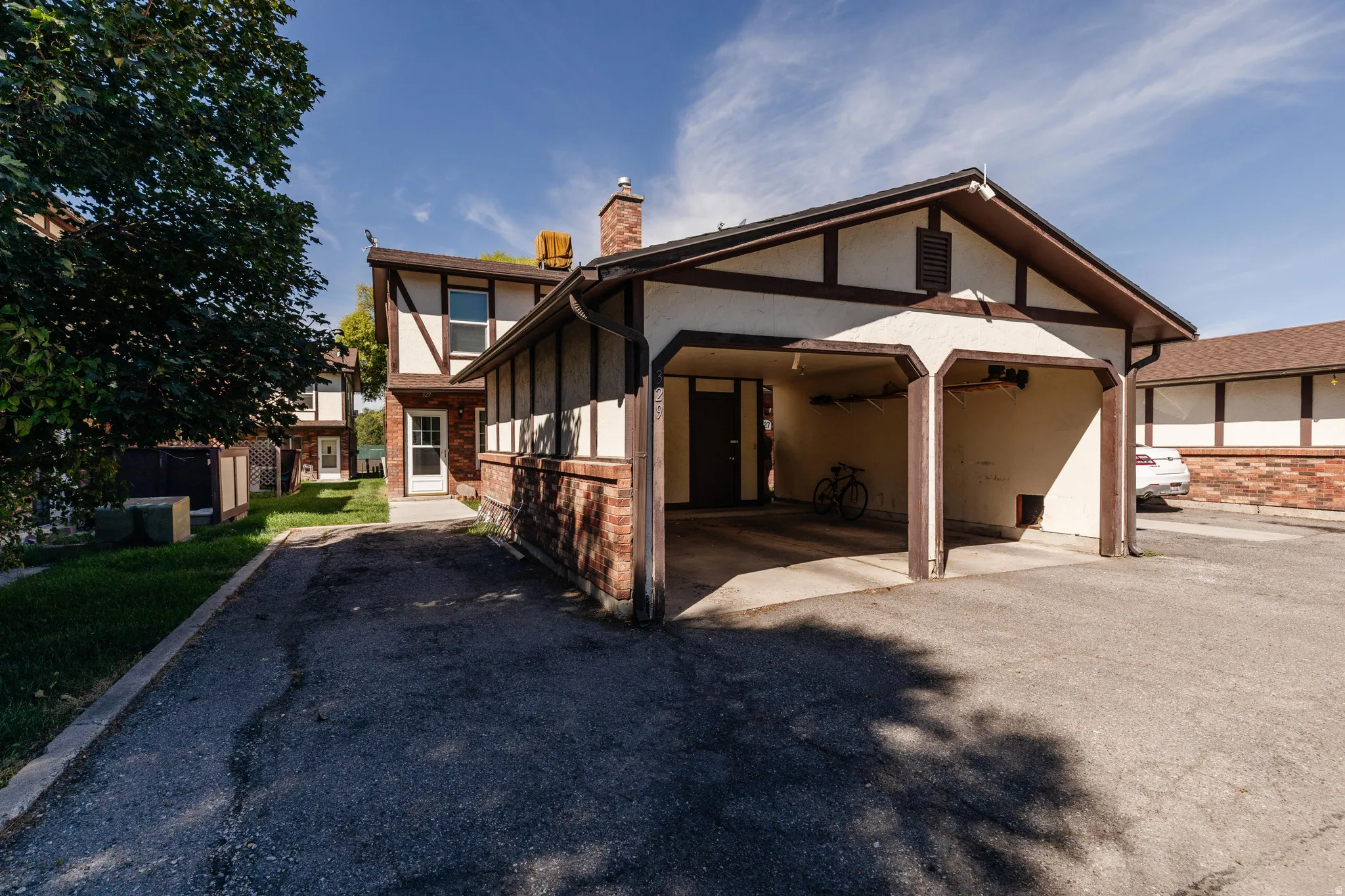 Tudor-style exterior featuring a carport and brick detailing
