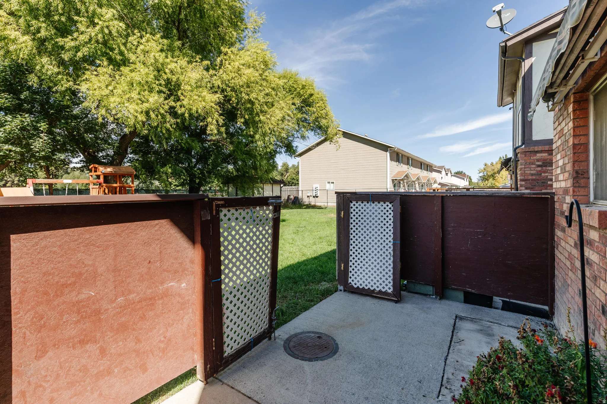 Concrete patio area featuring a privacy fence with lattice panels