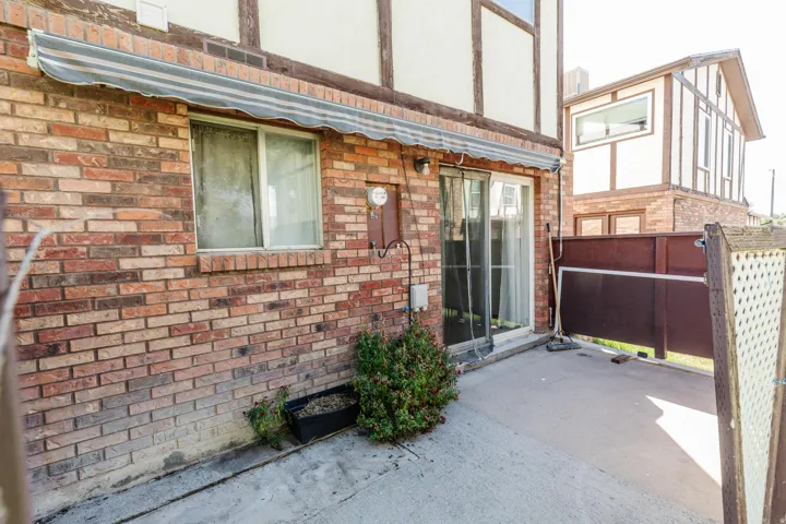 Brick exterior, sliding glass door, concrete patio, privacy screen, overhead awning