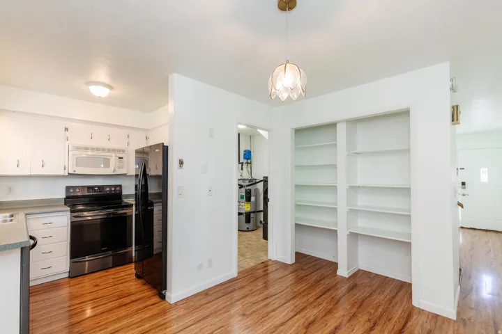 Kitchen featuring white cabinetry with silver hardware, black oven, microwave, and refrigerator