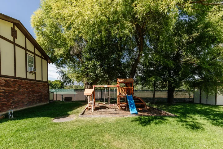 Expansive backyard featuring a lush lawn, mature trees, and a privacy fence