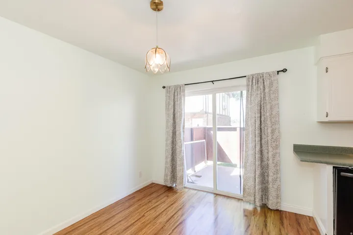Wood-finish flooring, overhead lighting fixture, sliding glass door, white cabinetry, and green countertop