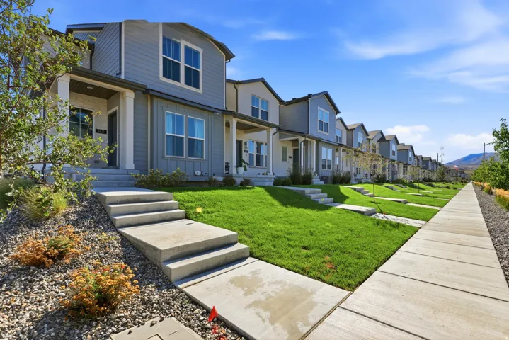 Contemporary townhome featuring a light gray siding exterior, white trim, and a covered front porch
