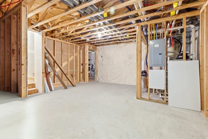Unfinished basement with exposed wood framing, concrete flooring, and visible utility installations