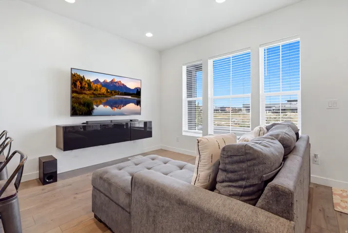 White walls with recessed lighting, wood-finish flooring, and a floating media console