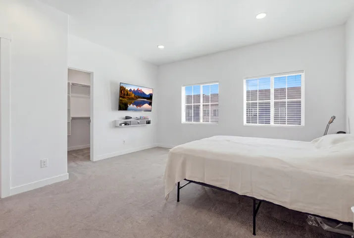 Recessed lighting, soft carpet flooring, dual windows with blinds, and an open closet with built-in shelving