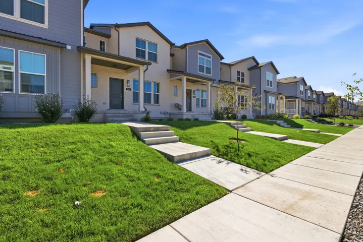 Row of townhomes featuring varied exterior finishes, covered front porches, and concrete walkways