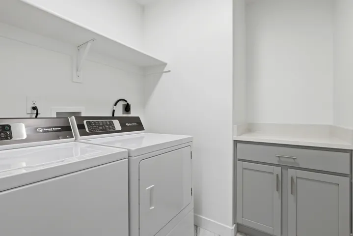 White wall-mounted shelving, gray cabinetry, and a light-toned countertop