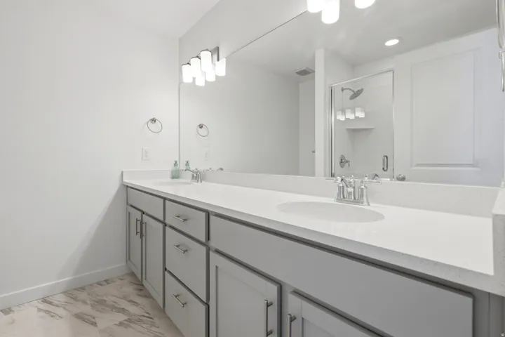 Dual sink vanity with light gray cabinetry and white countertops