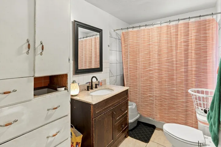 Built-in storage cabinetry, vanity with countertop and integrated sink, wall-mounted mirror, and ceramic tile flooring