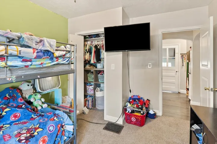 Carpeted room with a built-in closet featuring shelving and hanging space